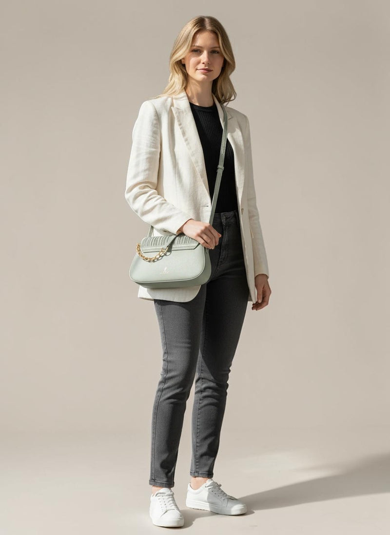 Model wearing ALESSIA JADE sage green Cypress shoulder bag with gold chain detail and adjustable strap in a bright room.